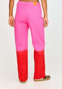 Spodnie z różowo-czerwonym gradientem o prostym kroju, wykonane z bawełny. Posiadają pas z szlufkami oraz kwadratową metkę z tyłu.