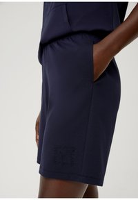 Marineblaue Shorts aus glattem Stoff, mit einer Seitentasche und geprägtem Schriftzug. Mit einem elastischen Taillenbund für zusätzlichen Komfort gestaltet.