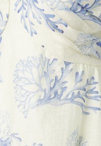 Tecido leve em branco com padrões de coral azul, apresentando uma textura suave e um design fluido que cai suavemente.