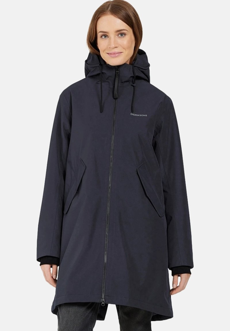 Giacca a vento di colore blu navy scuro, con zip frontale, cappuccio regolabile con stringa e due tasche laterali. Realizzata in tessuto liscio e resistente all'acqua.