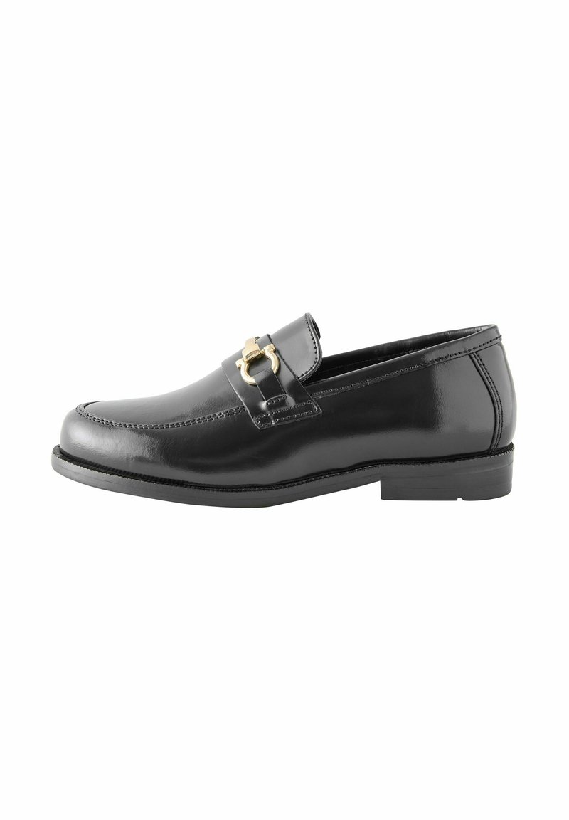 Mocassin en cuir noir avec une finition poli, présentant une boucle décorative en or sur la sangle et un talon plat bas. Coutures simples en accent.
