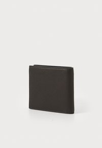 Billetera bifold de cuero negro de pie sobre una superficie blanca con costuras visibles en los bordes.