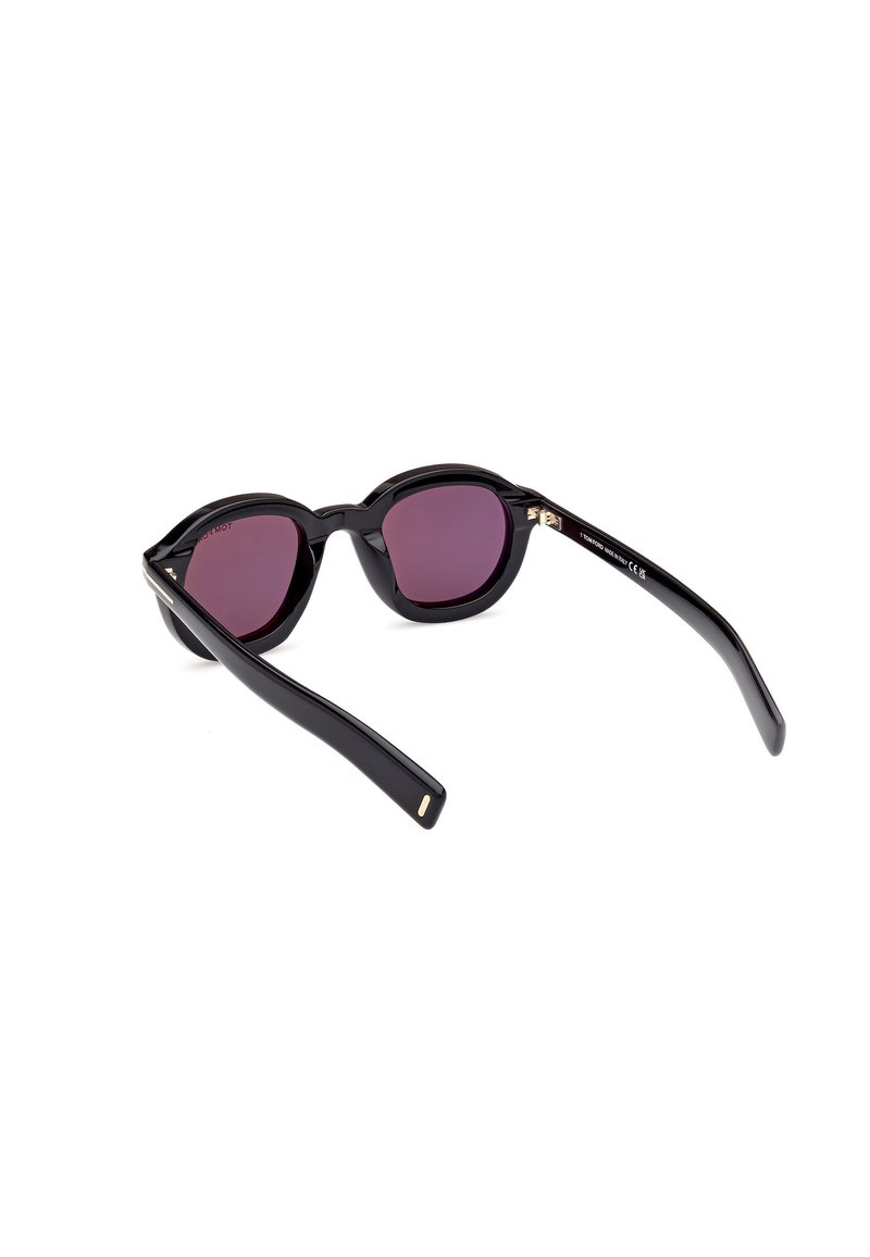 occhiali da sole neri con lenti tonde, sfumatura viola, e design elegante. Presentano dettagli dorati sulle cerniere e montature in plastica liscia.