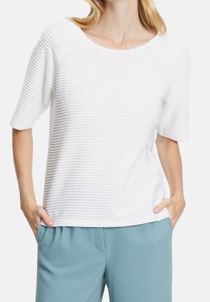 Top blanco de manga corta con textura acanalada, cuello redondeado y tela texturizada. Combinado con pantalones azul claro de corte relajado.