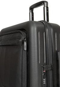 Valigia rigida nera con superficie texturizzata, manico estraibile, doppie cerniere e lucchetto a combinazione integrato sul davanti.