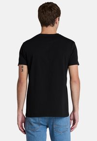 Maglietta nera in cotone con maniche corte e colletto rotondo, vista dal retro. Le caratteristiche di design notevoli includono un taglio dritto e una superficie liscia.