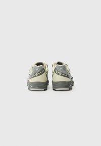 Chaussures de sport pour hommes avec une tige en mesh flexible, dans des tons beige et gris. Dotées d'une semelle rembourrée et d'un design minimaliste.