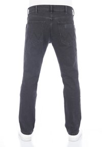Czarne jeansy z denimu o prostych nogawkach, z dwoma tylnymi kieszeniami ozdobionymi ściegiem w kształcie litery V oraz skórzaną naszywką na pasku.