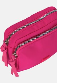 Trousse double zippée rose vif avec deux compartiments et tirettes en tissu assorties sur fond blanc.