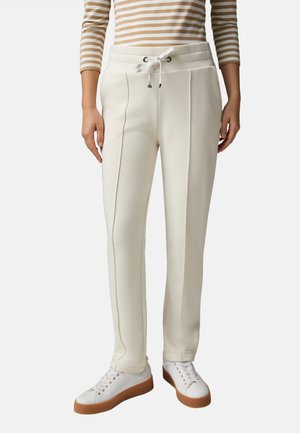 Pantaloni della tuta bianchi con vita regolabile, dotati di due tasche frontali e dettagli sui fianchi. Abbinati a sneaker bianche. Texture liscia.