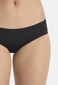 Schwarze Bikini-Unterhose aus weichem, dehnbarem Stoff. Sie verfügt über einen niedrigen Bund und ein minimales Design mit glatter Textur und ohne Muster.
