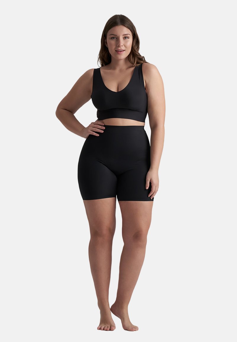 Completo activewear nero composto da top senza maniche e pantaloni corti a vita alta. Il tessuto liscio ha una finitura opaca senza motivi o hardware visibili.