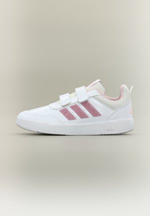 Άσπρο και ροζ αθλητικό παπούτσι Adidas με τρεις ροζ ρίγες, δύο ιμάντες με βέλκρο και λεπτομέρειες από δίχτυ στη φτέρνα και τη γλώσσα.