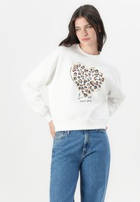 Weißes Sweatshirt mit einem großen Herzdesign in Leopardenmuster in Brauntönen und Pink, akzentuiert mit goldenem Rand und Text darunter.