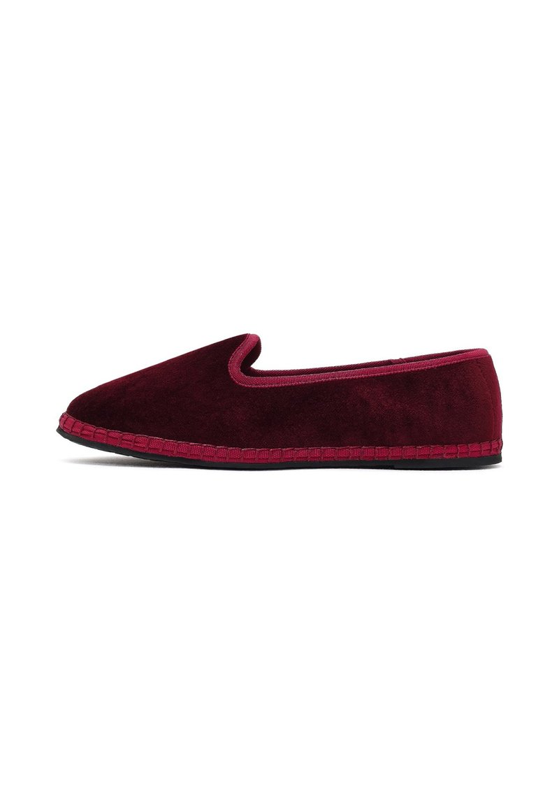 Mocassins en velours bordeaux avec une semelle noire et un bord bordeaux assorti, présentés de profil sur un fond blanc.