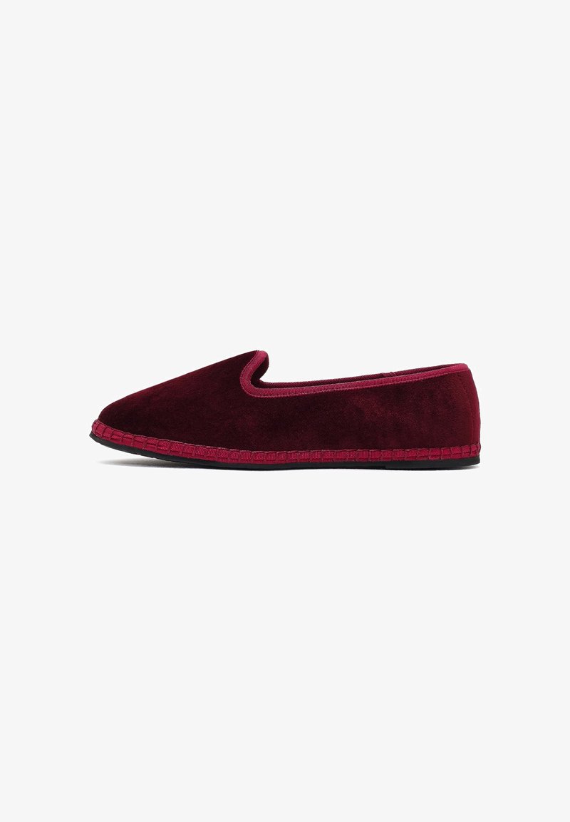 Mocassins en velours bordeaux avec une semelle noire et un bord bordeaux assorti, présentés de profil sur un fond blanc.