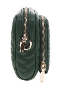 Sac en cuir vert matelassé avec quincaillerie en métal doré, fermetures à glissière doubles et une forme arrondie. Texture lisse avec un design structuré.