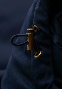 Marinekleurige stof trekzak met een messing sluiting en een zwarte koord, voorzien van een bronzen randje voor veilige sluiting en functionaliteit.