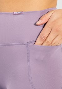 Leggings da allenamento lavanda con tasca laterale, texture del tessuto liscia e cuciture rinforzate vicino alla vita per una maggiore durata.
