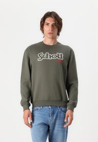 Felpa verde oliva con maniche lunghe, polsini e orlo a costine. Presenta un grande logo bianco "Schott" e un accento rosso "N.Y.C".