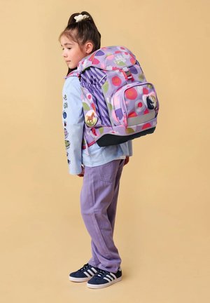 Mochila de diseño morado con acentos en rosa, dos bolsillos frontales, un bolsillo lateral; un detalle adicional incluye un pin decorativo en la parte frontal.