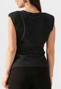 Zwart mouwloos topje met licht gewatteerde schouders, voorzien van een gestructureerde afwerking en subtiele glitteraccenten, getailleerd bij de taille.