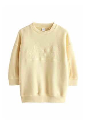 Sweat-shirt texturé jaune clair à col rond avec manches longues et texte embossé "New York Fifth Ave Since 1982" sur le devant.