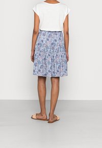 Blue patterned skirt with a tiered design, paired with a light-colored t-shirt. Footwear is light brown, flat sandals.