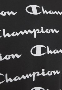 Czarna tkanina z powtarzającym się białym napisem "Champion" w kursywie, z okrągłym logo i gładką teksturą.