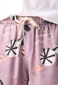 Shorts à cordon de serrage violet clair avec des motifs abstraits en noir, blanc et rouge. Confectionnés dans un tissu doux avec une coupe décontractée.