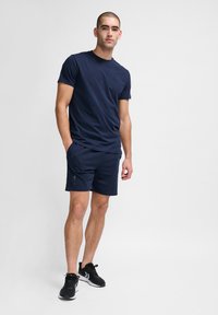 Marineblauw t-shirt en short set, gemaakt van zachte stof. Het t-shirt heeft een borstzak; de short heeft een accentlogo aan de linkerkant.