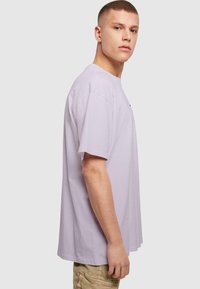 Lyse lavendel kortærmet t-shirt lavet af bomuld. Løs pasform med rund halsudskæring, lidt længere bagkant og uden fremtrædende mønstre.