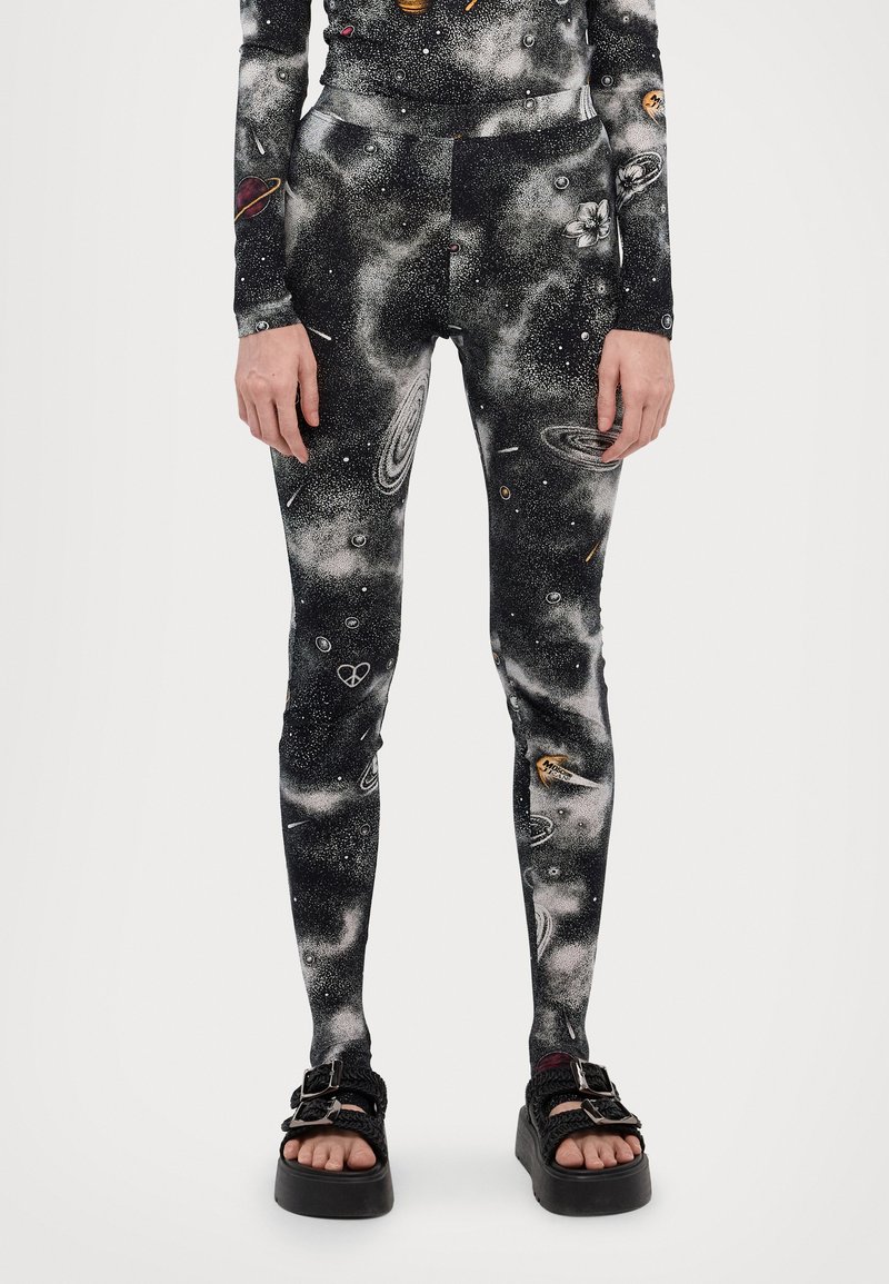 Leggings negros con un estampado de galaxia, que presentan planetas y estrellas. Están hechos de un material elástico, tienen una textura suave y un diseño ceñido.