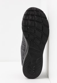 Semelle de chaussure de sport noire avec un motif en caoutchouc texturé ; tige grise à l'aspect tissé ; design léger et flexible.