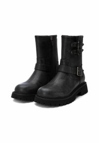 Botas negras hasta el tobillo de suave cuero sintético, con acentos de doble hebilla, cremallera lateral y una suela de goma gruesa con dibujo.