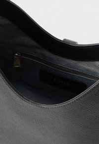 Pelēkas krāsas ādas soma ar teksturētu virsmu, gludu malu, iekšējo rāvējslēdzēja kabatu un zīmola etiķeti.