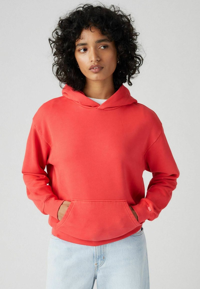 Roter Hoodie mit Kängurutasche, langen Ärmeln und einer Kordelzugkapuze. Hergestellt aus weichem Stoff, bietet einen lockeren Schnitt und ein minimales Design.