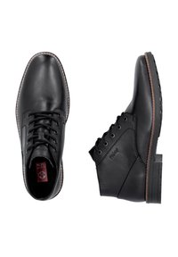 Chaussures noires en cuir avec une finition lisse, bout rond, fermeture à lacets et une semelle robuste avec des accents de couture marron.