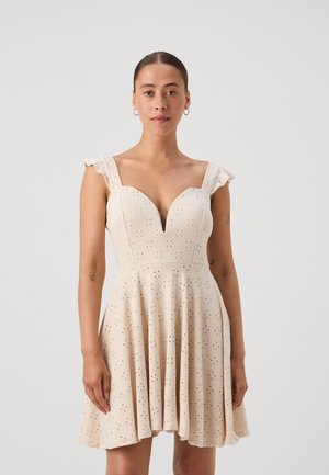 Cream-colored dress with a fitted bodice, V-neckline, and flared skirt, featuring eyelet details and ruffled straps.
