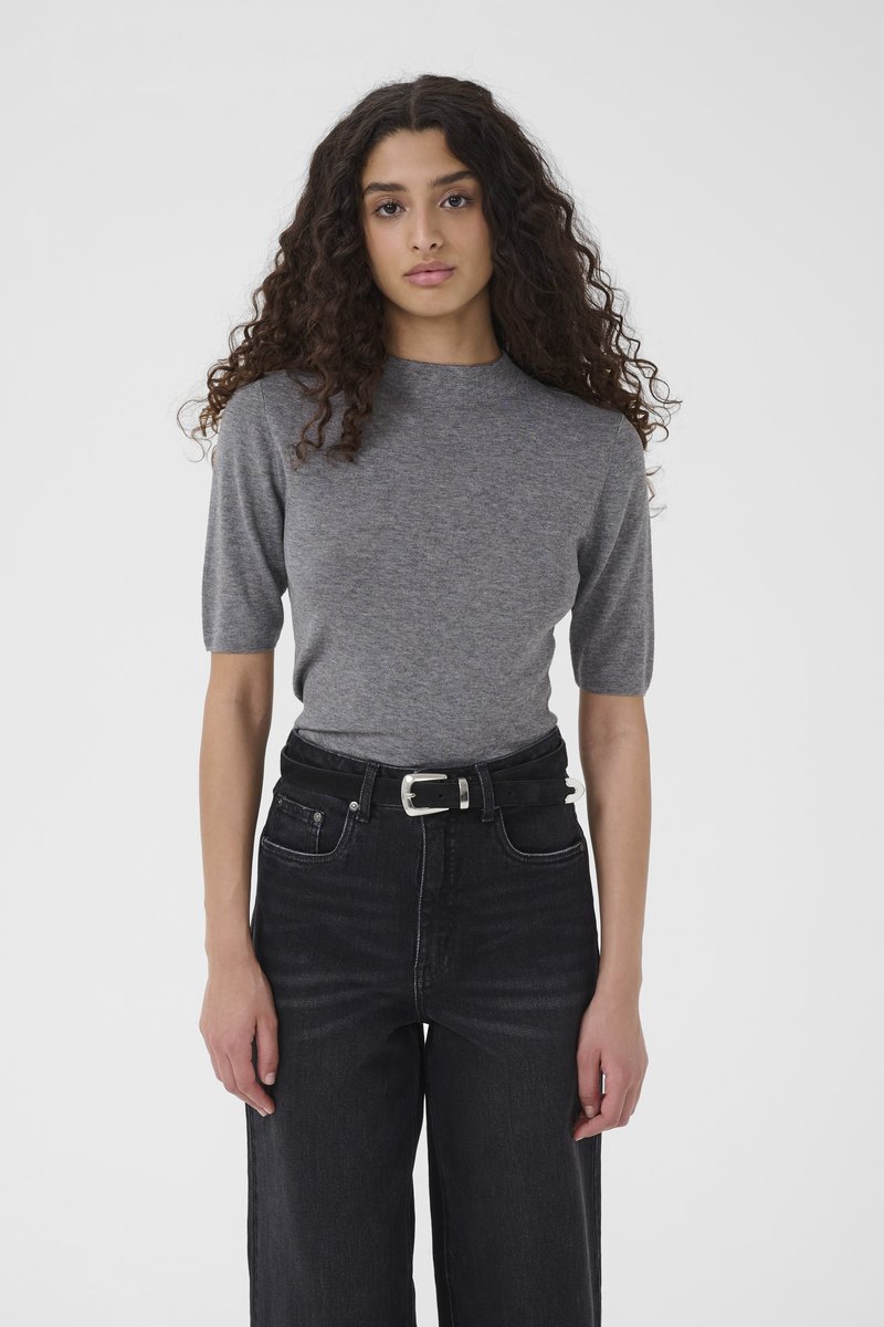 Top grigio a maniche corte con scollo rotondo, abbinato a jeans neri a gamba larga e vita alta e a una cintura nera con fibbia argentata.