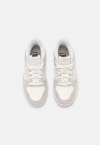 Baskets blanches et gris clair avec un bout en daim, des panneaux latéraux en cuir et des détails perforés. Équipées de lacets plats blancs et d'une semelle en caoutchouc.