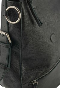 Borsa a tracolla in pelle nera con superficie texture, dotata di chiusura con zip, accessori circolari e tracolla regolabile.