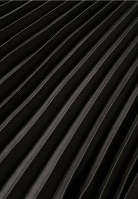 Tela negra plisada con ranuras verticales y textura suave, que crea una apariencia estructurada con un brillo sutil y profundidad.