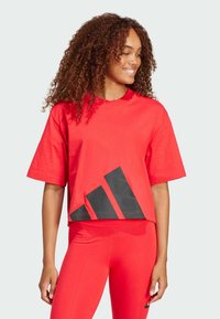 Röd kortärmad t-shirt i bomull med en svart triangel-design vid fållen, korta ärmar och rund halsringning.