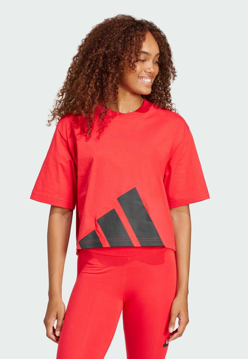 Röd kortärmad t-shirt i bomull med en svart triangel-design vid fållen, korta ärmar och rund halsringning.