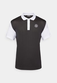 Čierna polo košeľa s bielym golierom a rukávmi, so zaobleným logom na hrudi. Vyrobená z hladkej látky s klasickým strihom.