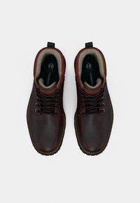 Brown leather ankle boots with black laces, padded collar, and a logo on the insoles. Features a textured rubber sole.
