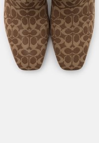 Bottes cheville marron à motifs avec une texture en tricot lisse, un bout pointu et un motif géométrique couvrant la surface supérieure.