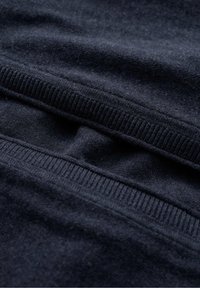 Temno moderna pulover s svojo mehko teksturo. Ima rebrast ovratnik in rob, prikazuje gladko tkanino z rahlimi šivi.