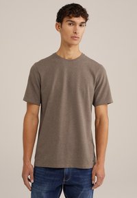 Tricou cu mânecă scurtă, cu gât rotund, dintr-un material maro texturat. Prezintă o croială lejeră și o cusătură decorativă subtilă pe margine.